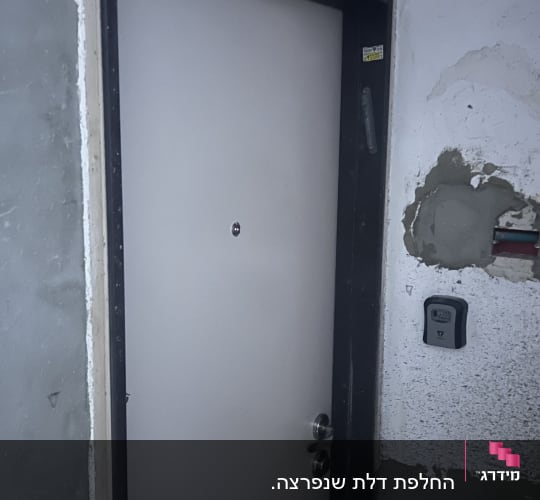 דלת כניסה מפלדה מותקנת בפתח בית עם משקוף כהה